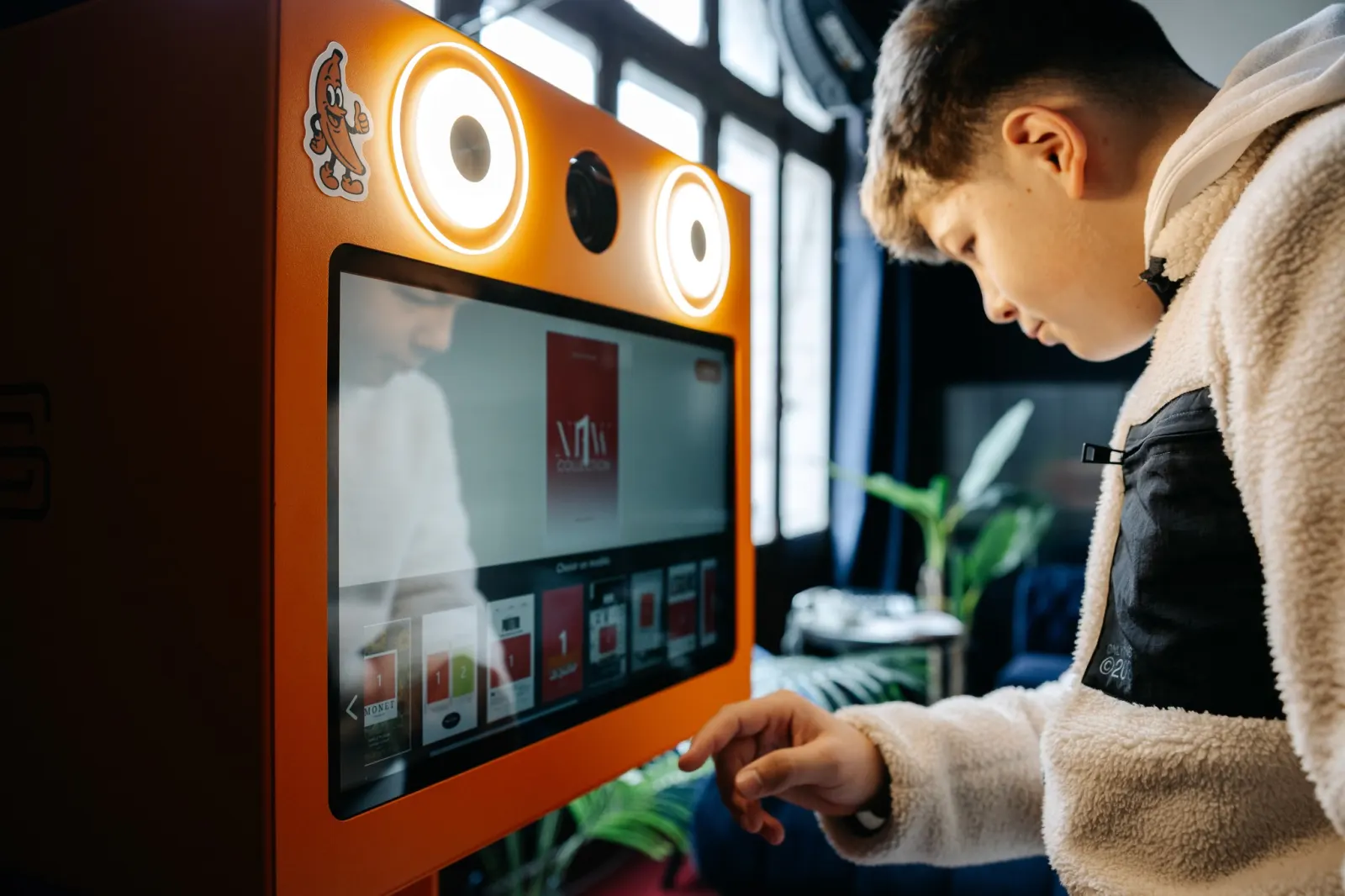 Un invité utilise l’écran tactile du photobooth orange ClickClickbox